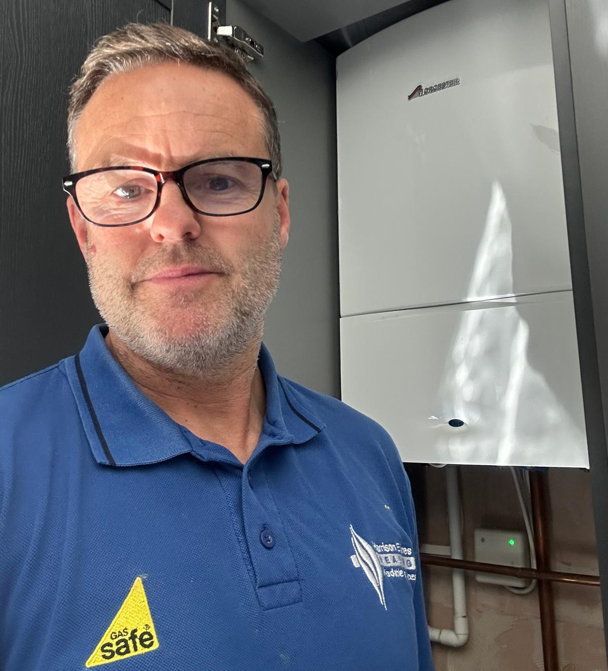 Gas Safe registered engineer from Harrison E Jones Heating beside a newly installed boiler